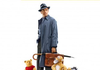 Christopher Robin (Ewan McGregor) stands in a fedora and trenchcoat, holding a suitcase and umbrella. He is surrounded by Winnie the Pooh, Tiger, Piglett, and Eeyore