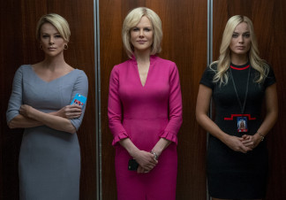Three women (Charlize Theron, Nicole Kidman, Margot Robbie) stand together in an elevator lift. All three are staring ahead, two are holding mobile phones, while the one on the right clutches her hands nervously