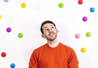 A man cheerfully looks up while surrounded by colourful balls